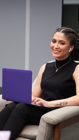 Computer Science student sitting and smiling with laptop