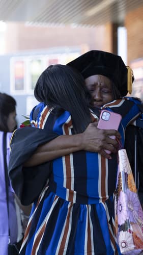 Doctoral Graduate Hugs Family Member After Receiving Diploma