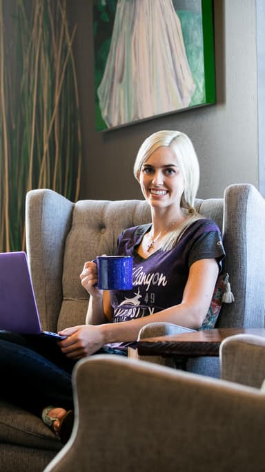 Female online degree graduate from GCU working on laptop in home office