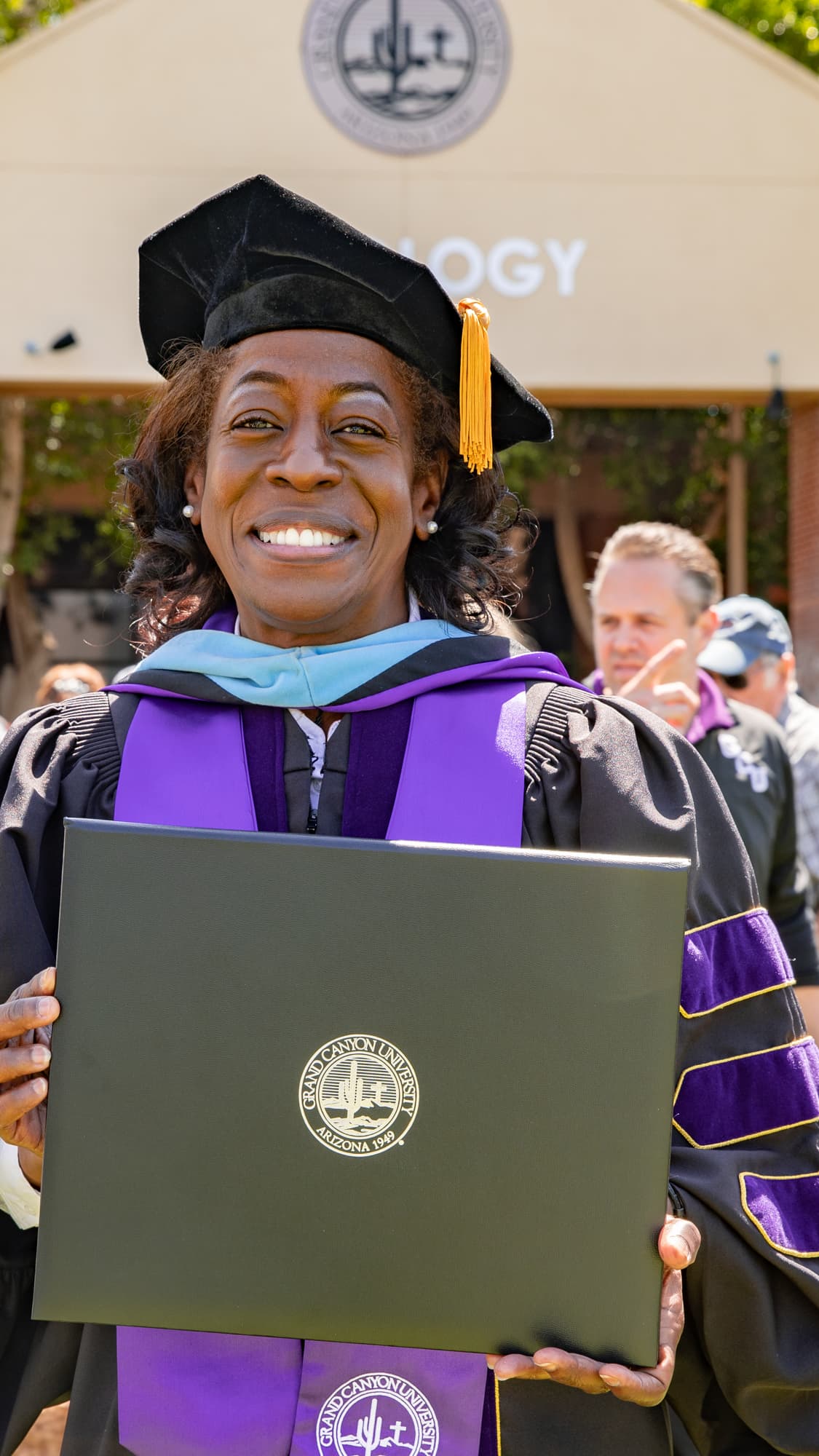 Female GCU student smiling and holding diploma at graduation