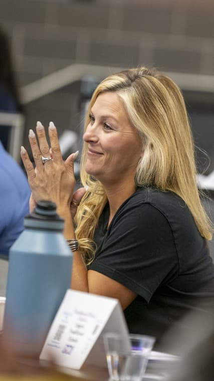Blonde smiles listening to a speaker in a doctorate level cohort environment