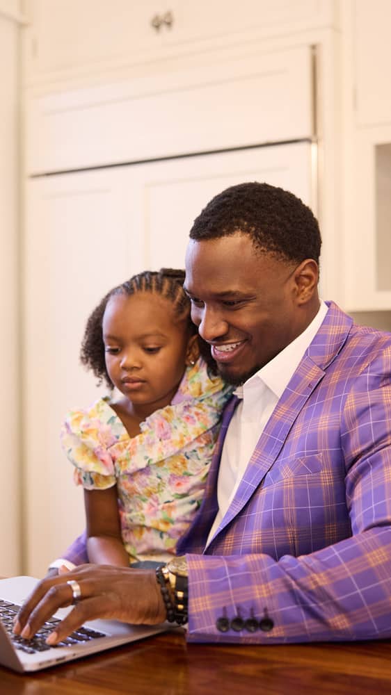 Man sitting with young daughter at kitchen table while applying for online degree
