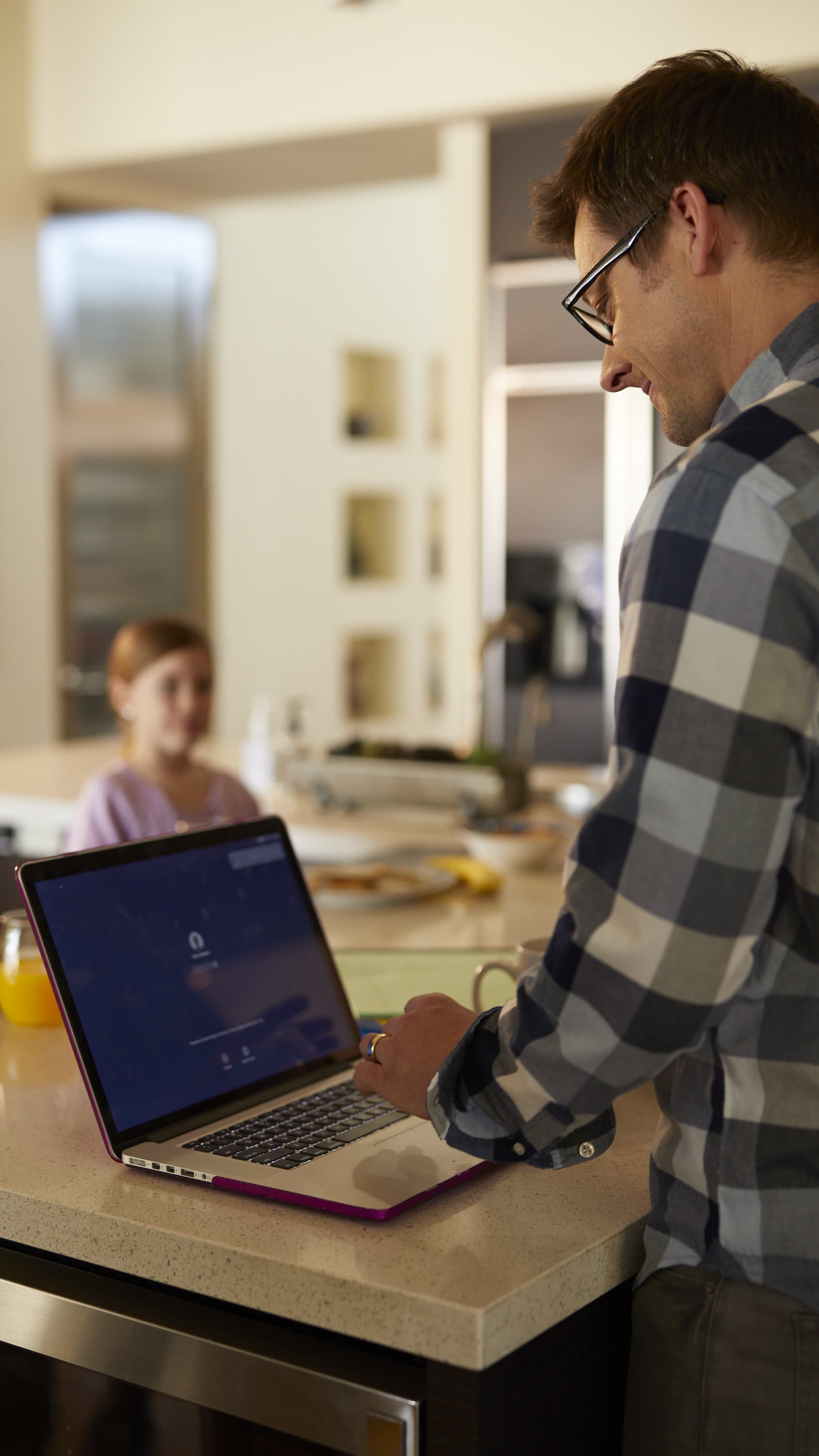 Online doctoral student completing work online in kitchen with daughter