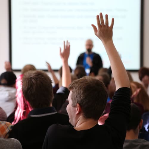 honors students raising their hands in class
