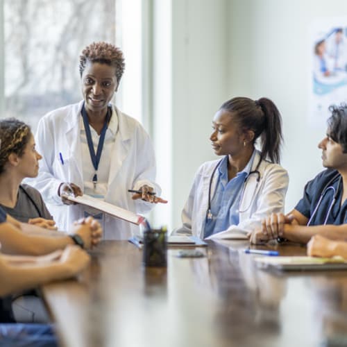 Mental health professional leads boardroom discussion on behavioral healthcare.