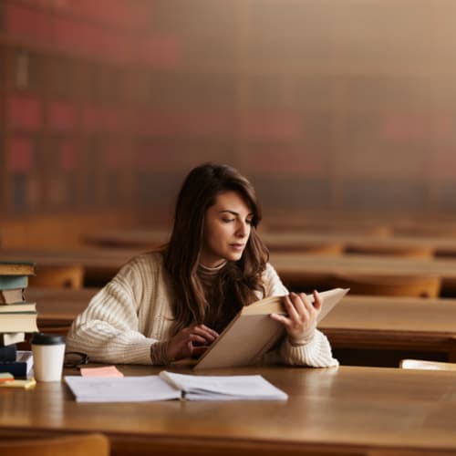 student reading in a library by herself
