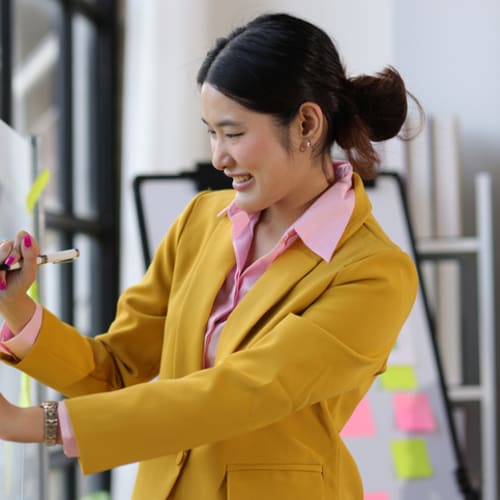 Woman brainstorms on a board with sticky notes.