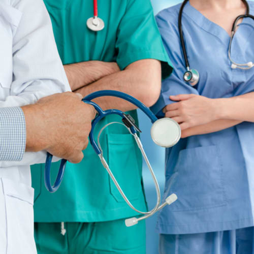 DNP vs NP students in scrubs and white coat holding stethoscope