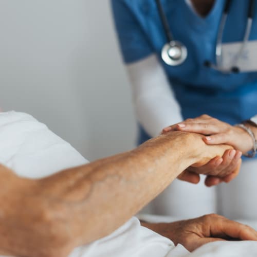 Nurse holding senior patient's hand