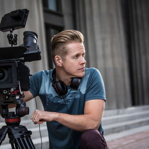 man kneeling next to a camera during filming