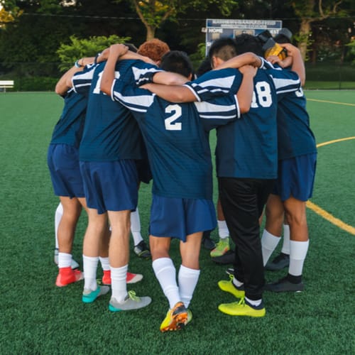 college soccer players having a team huddle before game