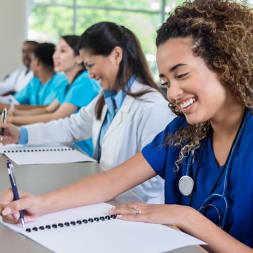 Nursing student writing on paper in class with peers