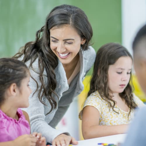 Smiling female teacher helping students