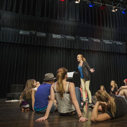 theatre student rehearsing in front of other students on stage