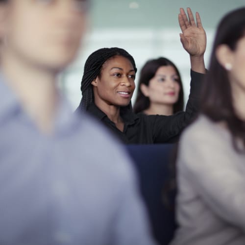 DBA and/or MBA student raising hand in classroom