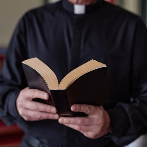 Close-up of priest reading Bible book during ceremony standing near the altar in church