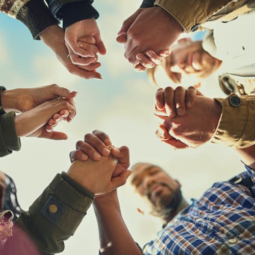 Shot of a group of friends putting their hands together in prayer