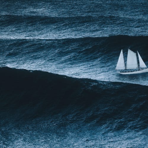 White sailboat sailing on large waves