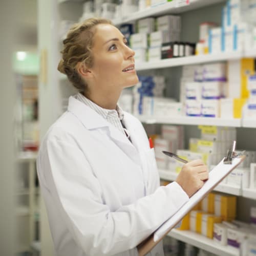 Pharmacist writing on clipboard - stock photo