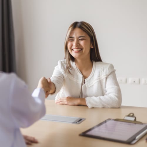 A young female being interviewed and shaking hands with the interviewer