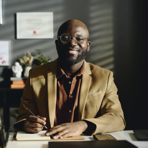 Male professional at desk with degrees on wall