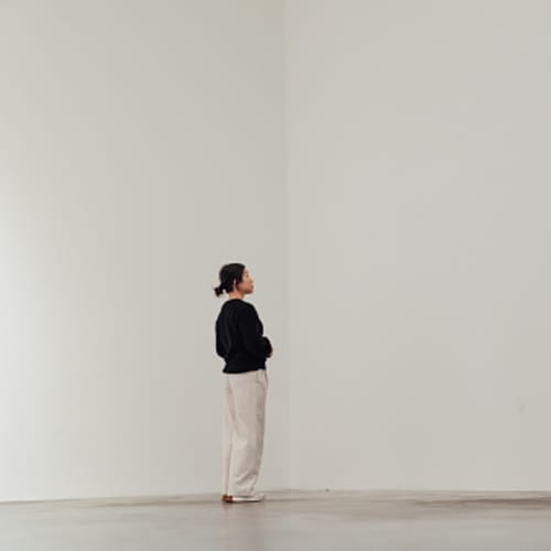 A simple white room with a Woman wandering.