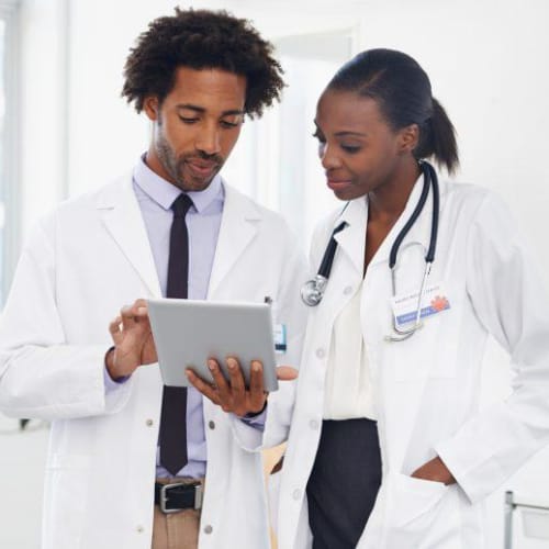 Two African-American doctors review results on tablet