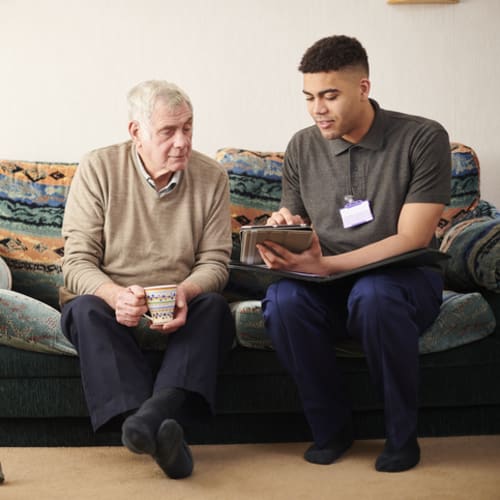 young male social worker meeting with elderly male client on couch