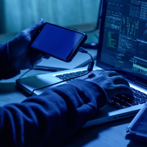 Hacker with mobile phone and computer