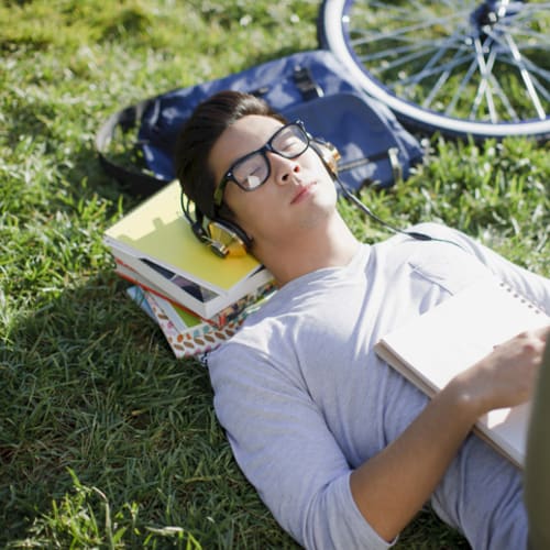 Student listening to music and relaxing on grass outside