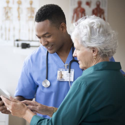 Male nurse reviewing information with elderly female patient.