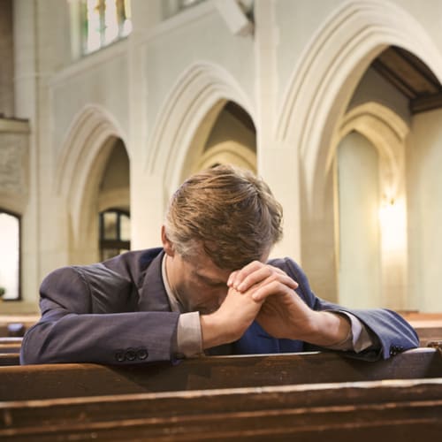 Man bows his head to pray in church for forgiveness
