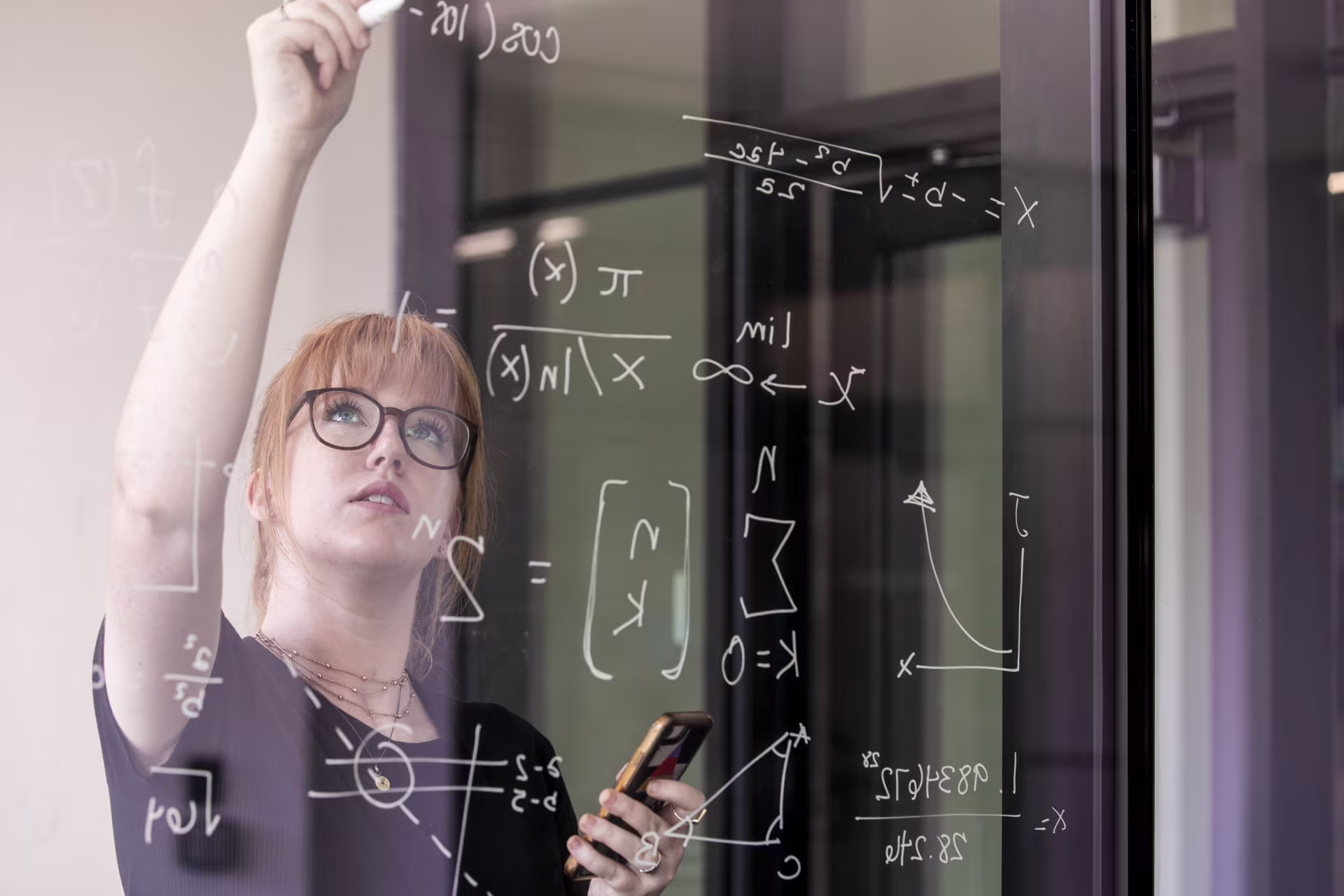 GCU mathematics student writing on a glass wall