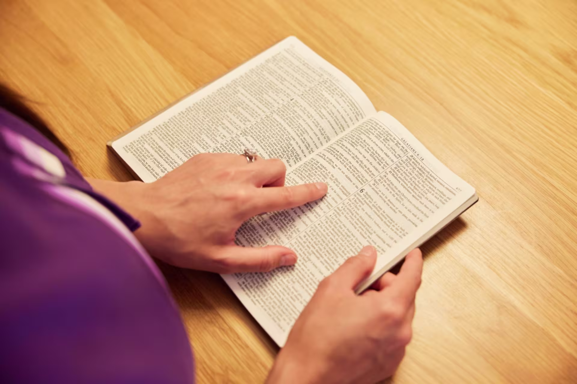 Woman’s finger scanning text to read on open bible