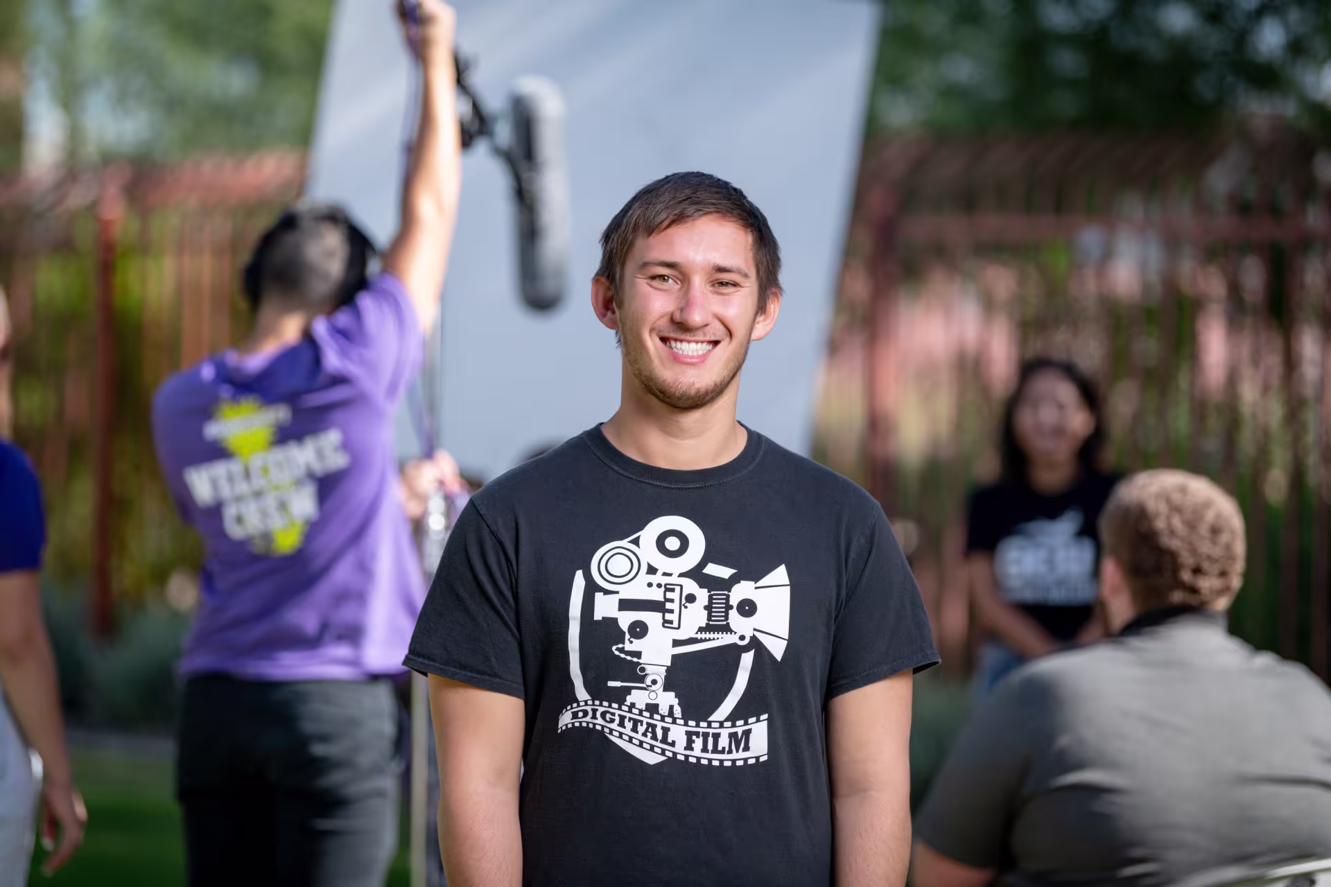 Male digital film production major smiling outside on set