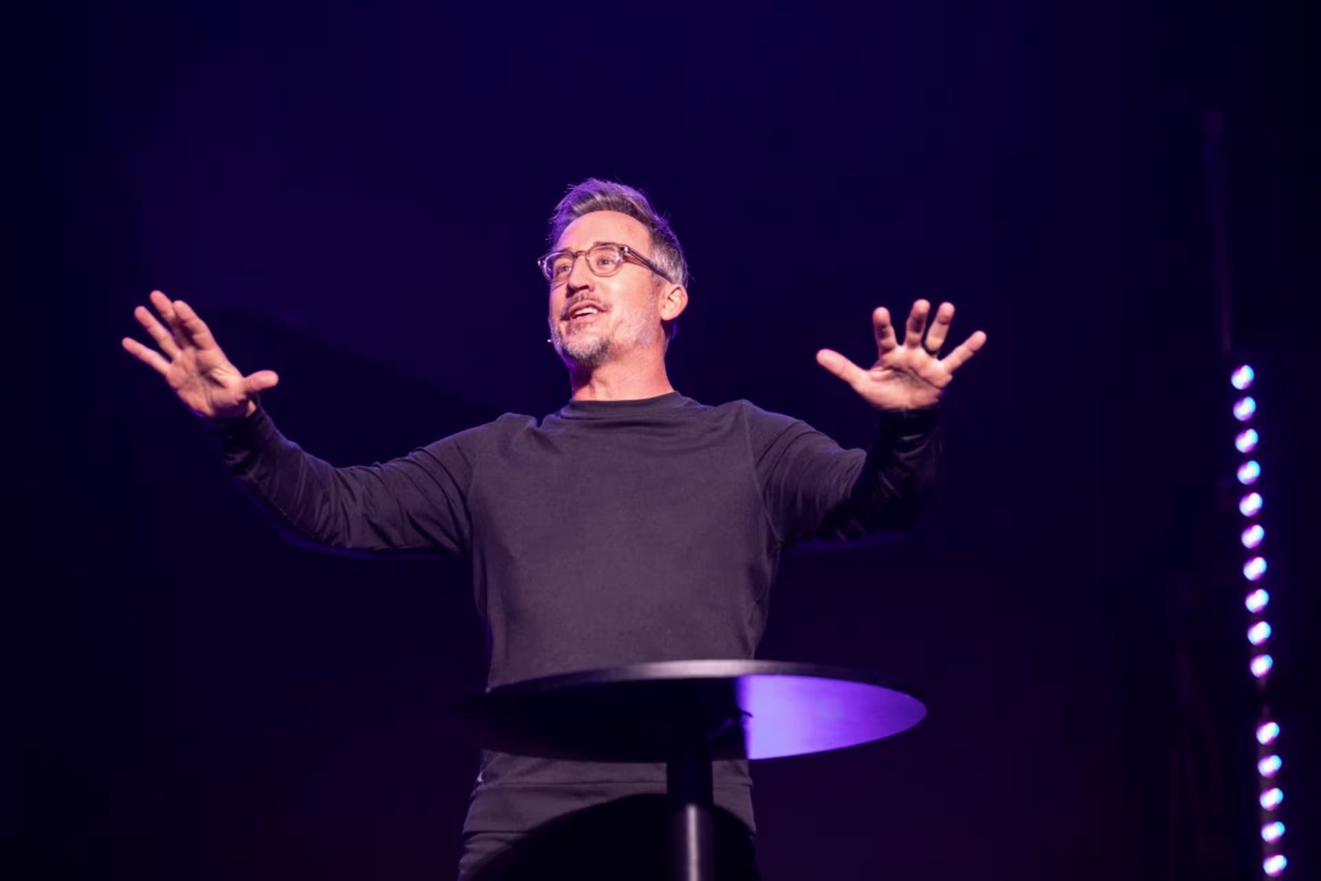 Pastor on stage leading worship with hands up