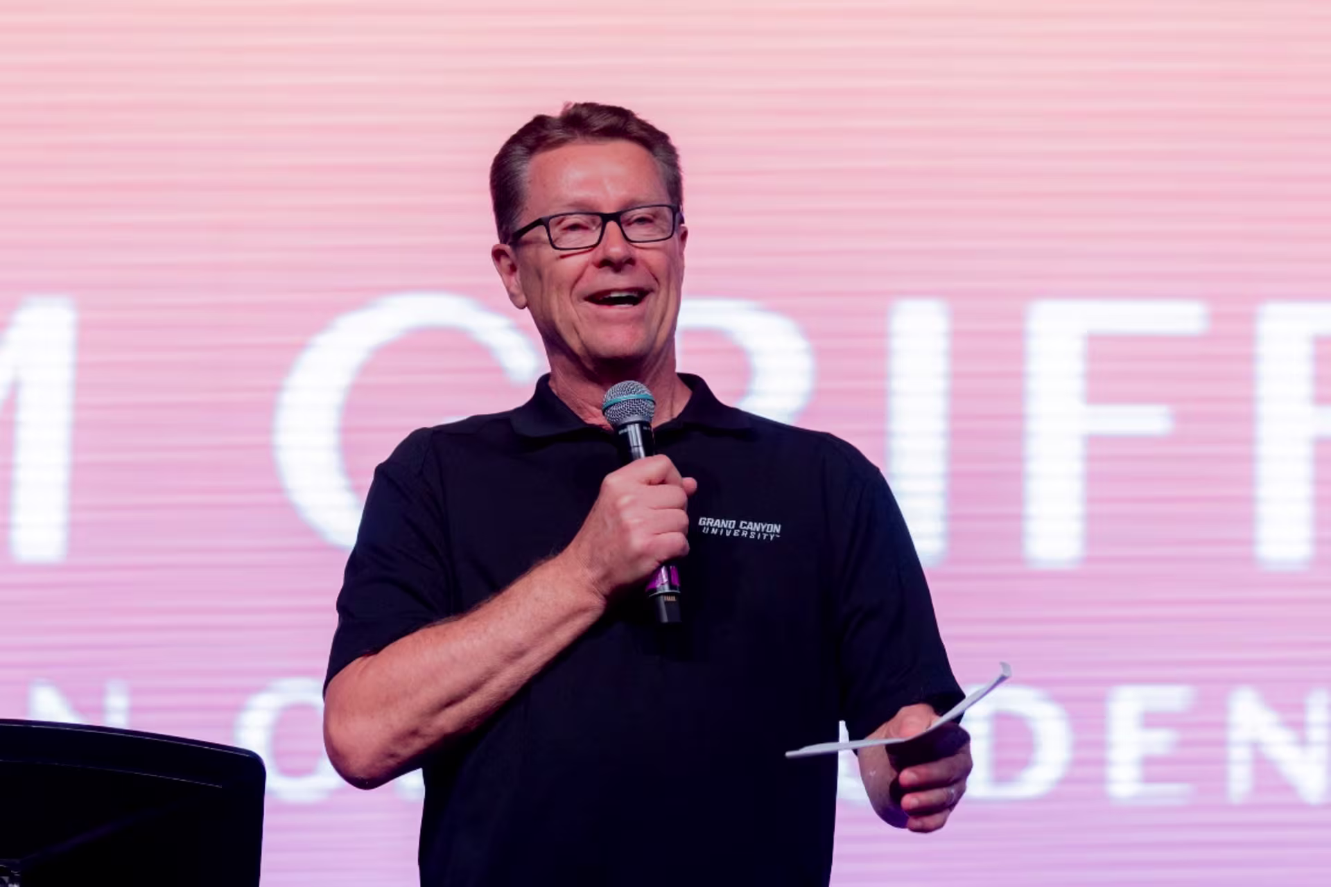 Pastor standing in front of crowd leading worship smiling