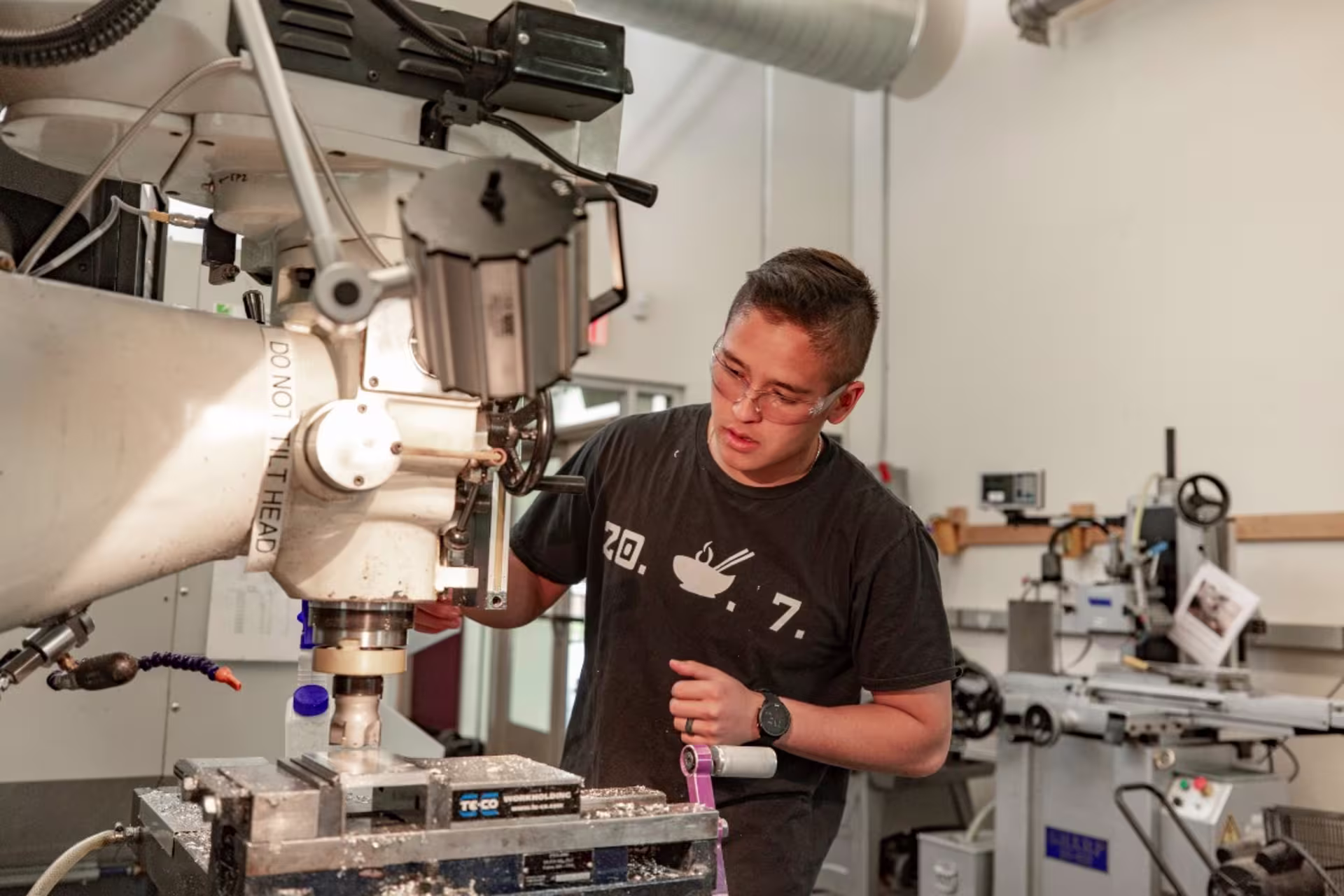 Engineering student in lab setting working on machine