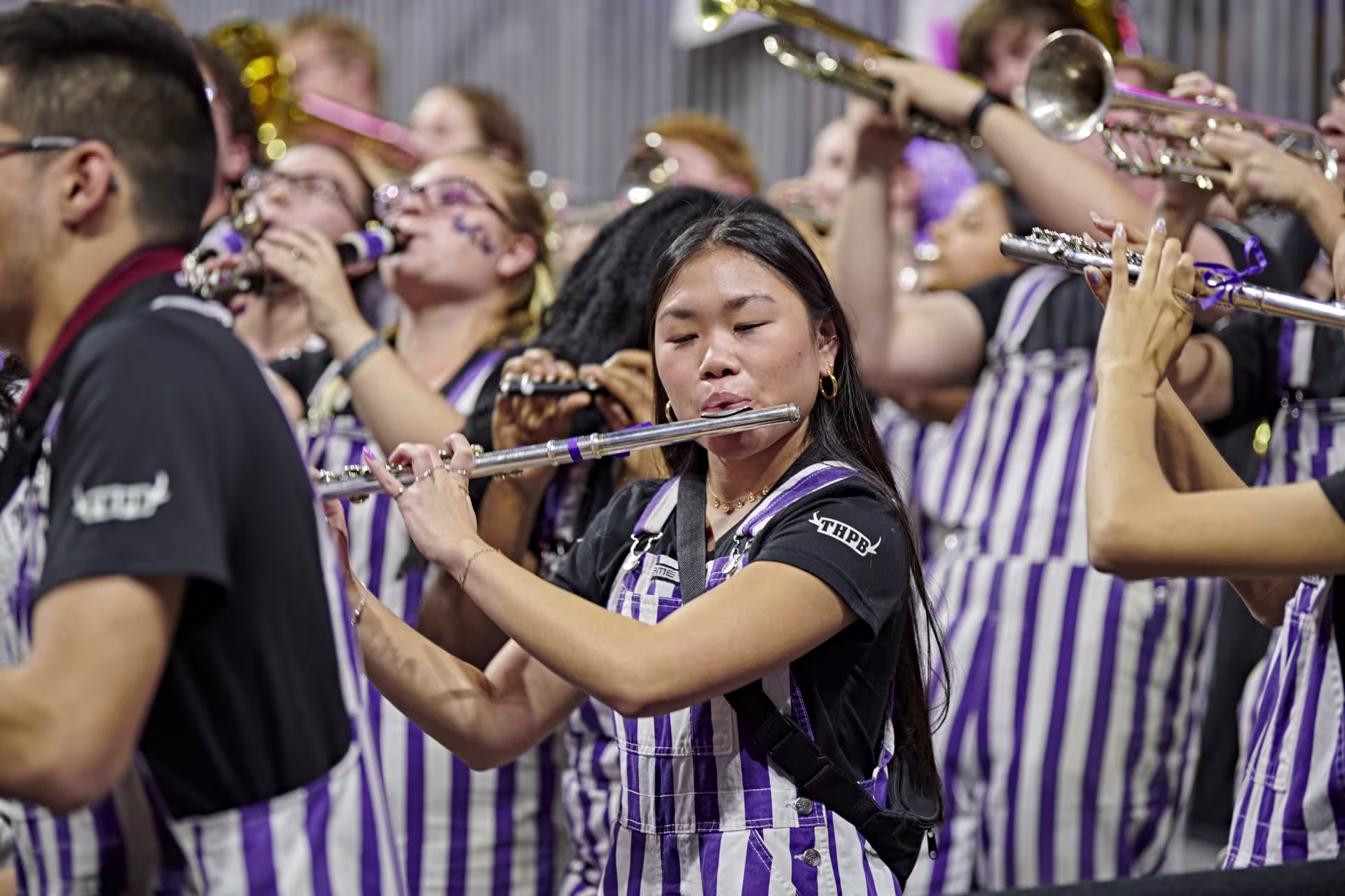 Focused shot of female flutist performing among group of music students