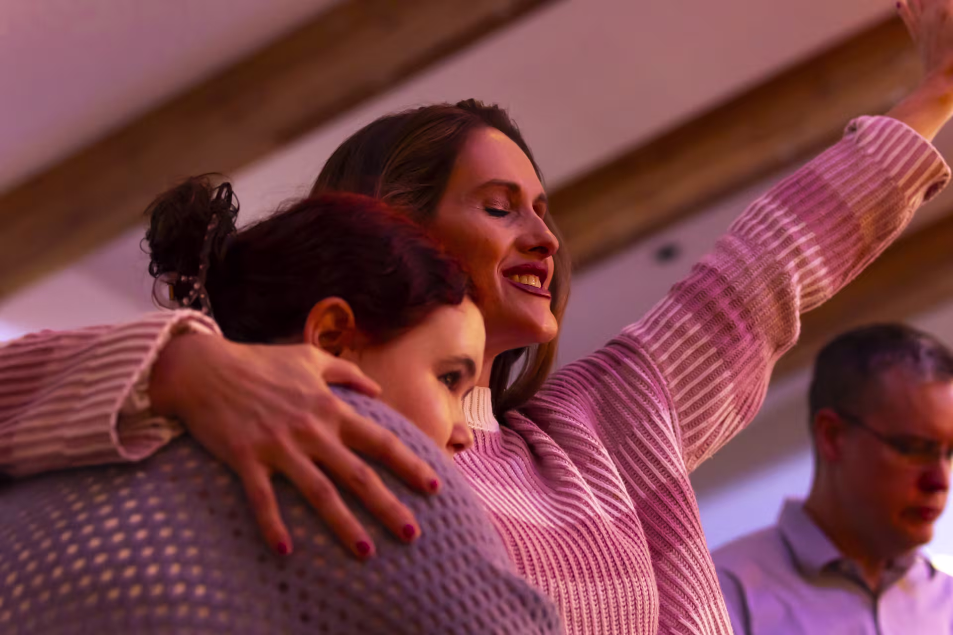 Female ministry leader and member hugging during worship