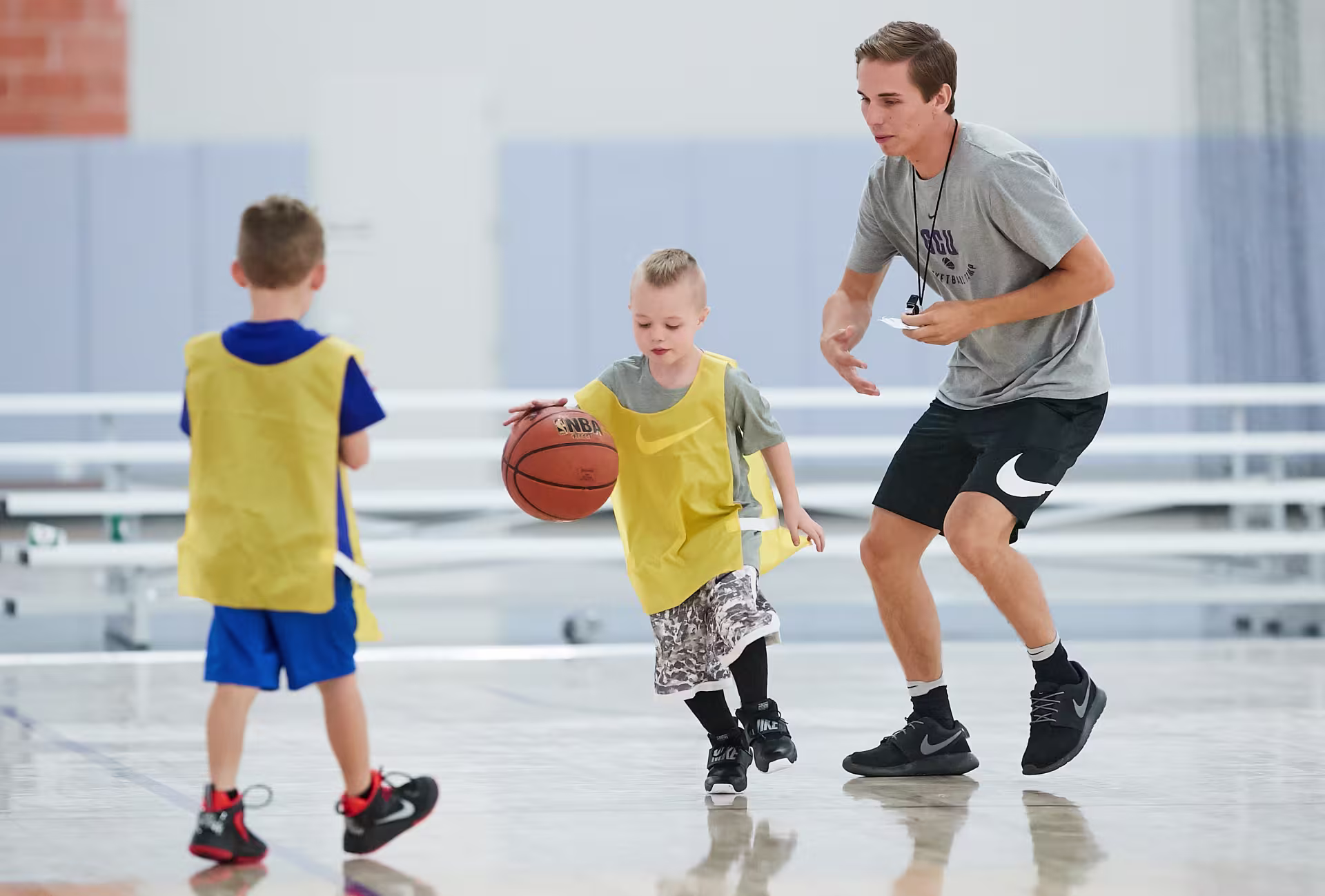 Male physical education major coaching two young basketball players