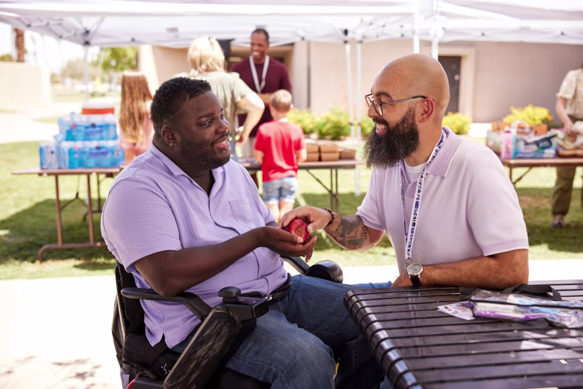 men sitting outside smiling and passing an apple in their hands