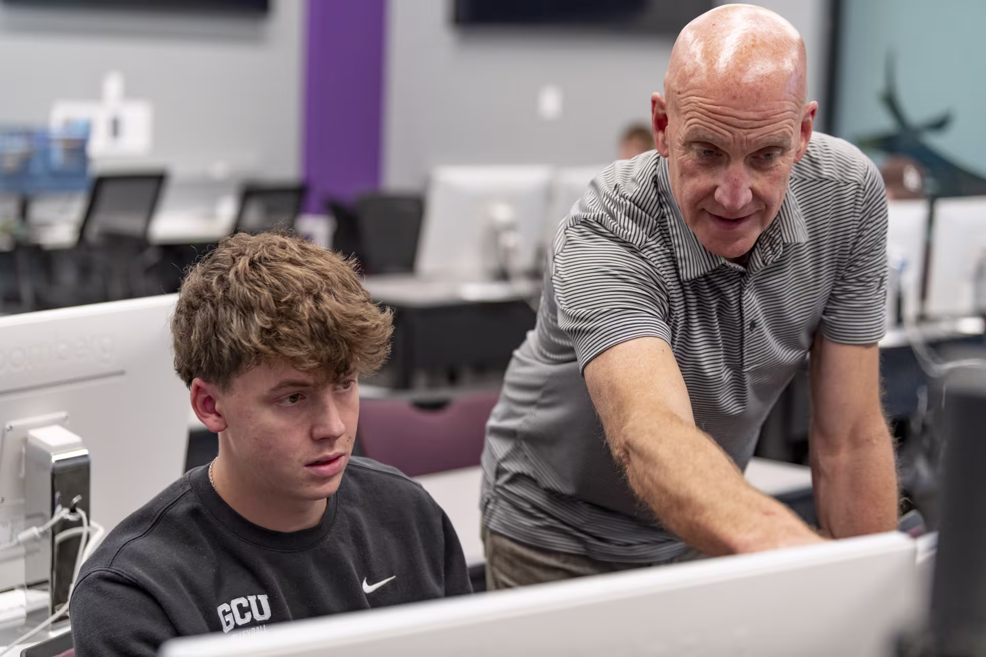 GCU student and professor collaborating in a computer lab, demonstrating hands-on learning in the BS in Finance and Economics program.