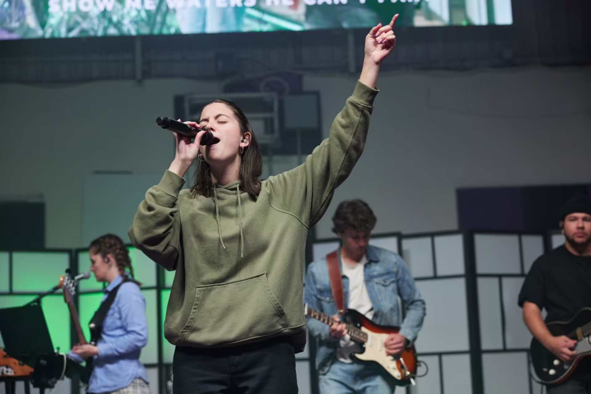 GCU student worshiping on stage with microphone and hand up