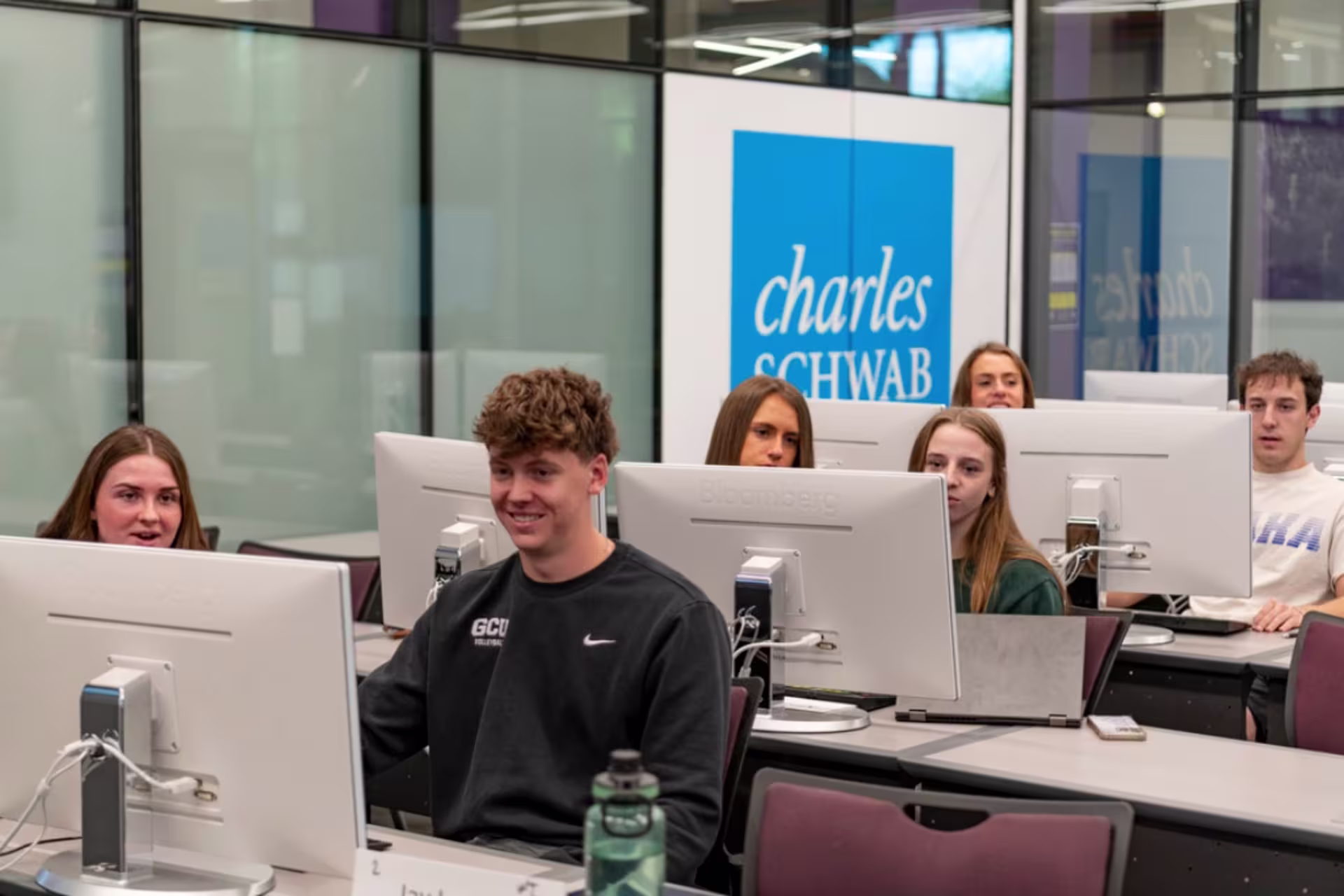 Finance students sitting at computers smiling in classroom setting