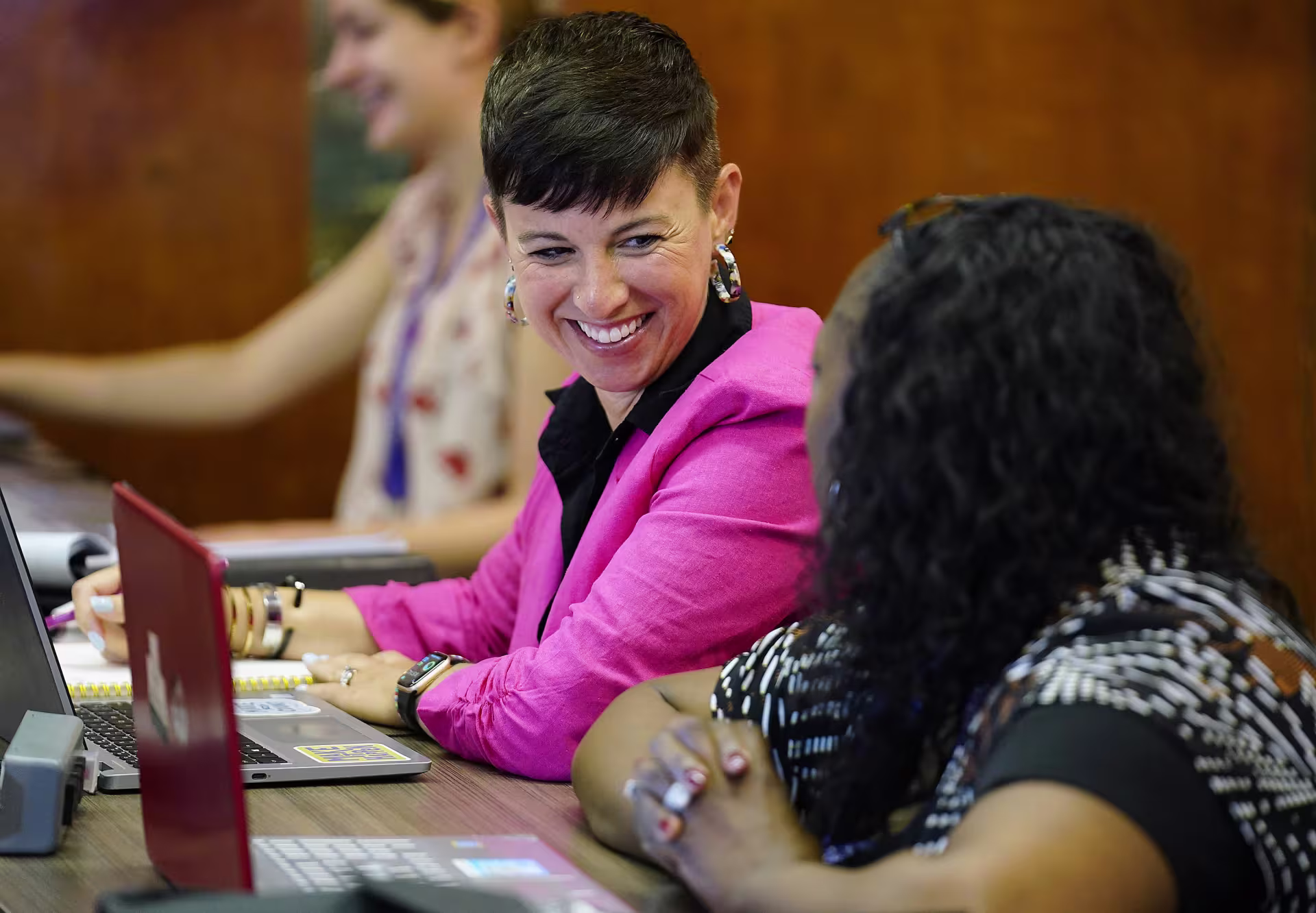 Three female DBA students collaborating on group assignment in class