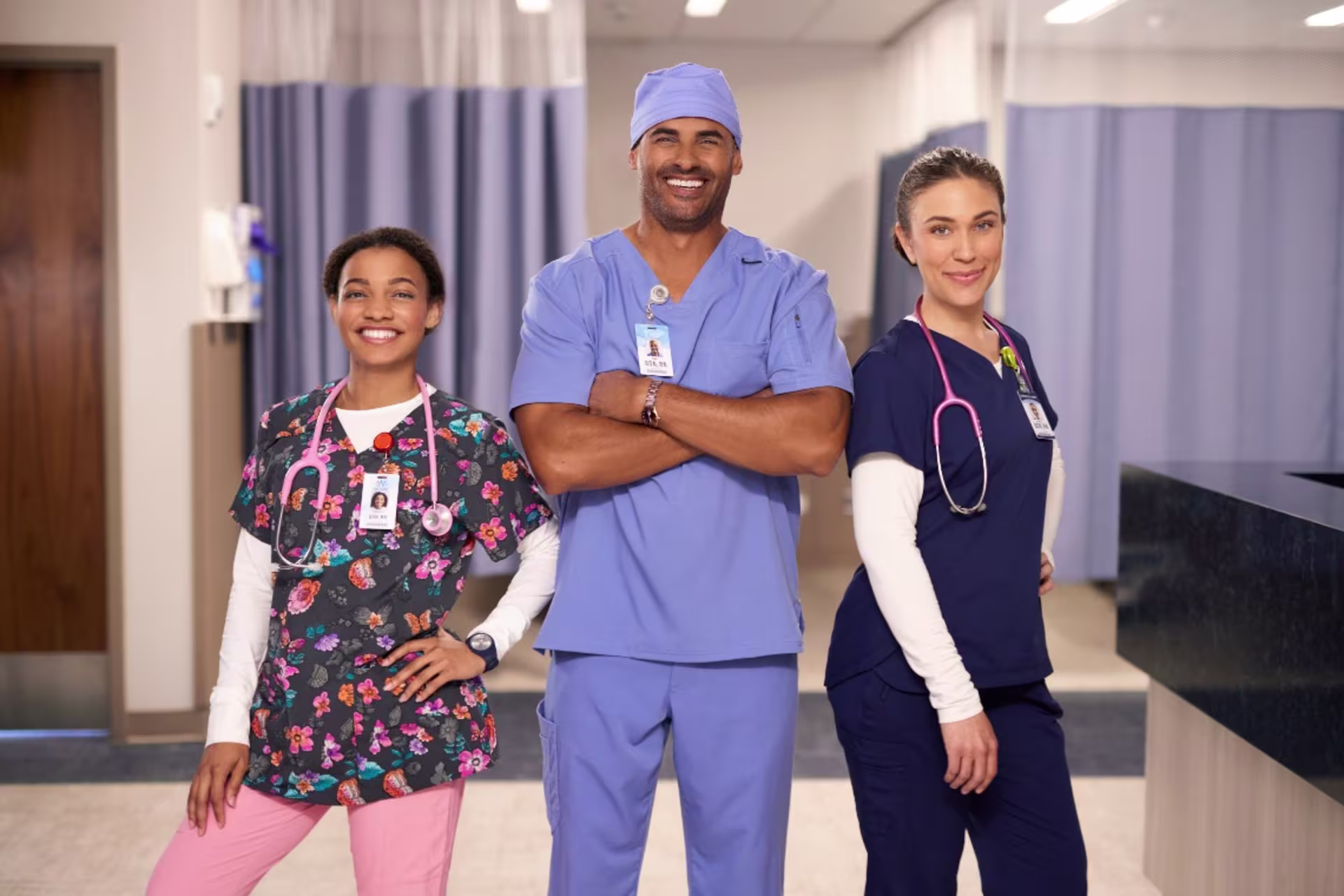 three nurses in different colored scrubs standing in hospital together