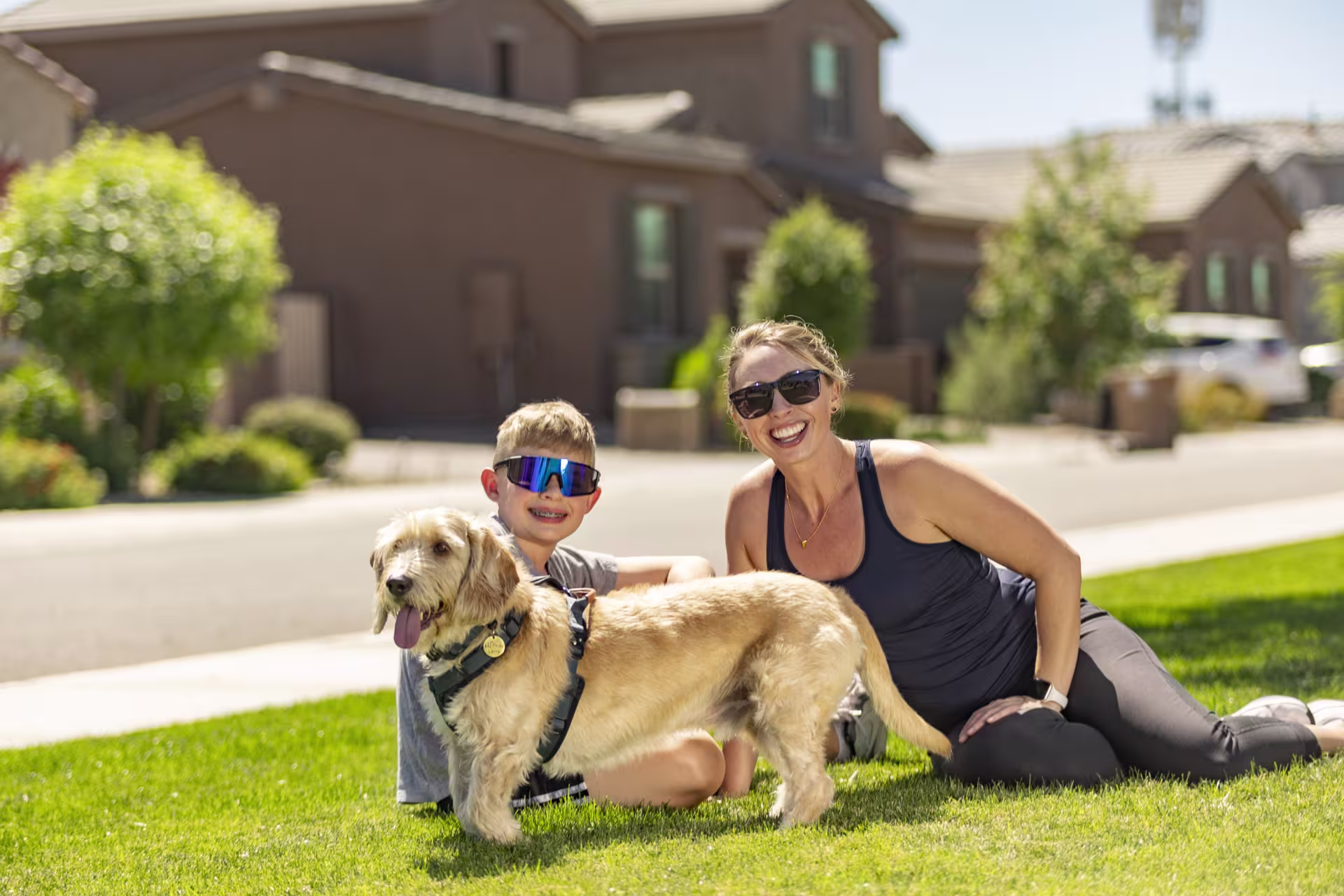 Woman and son sitting and smiling on grass with dog