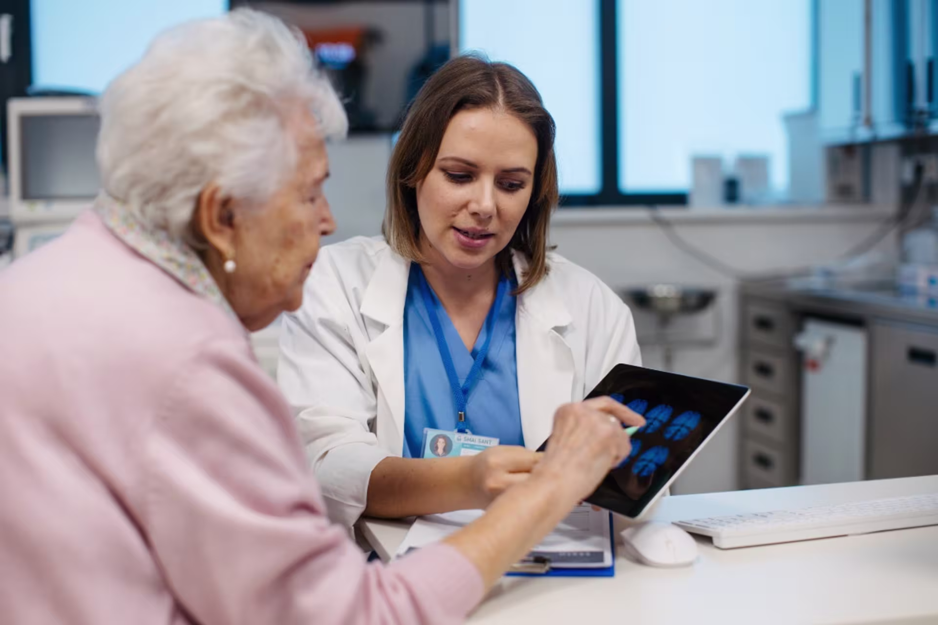 Behavioral health aid in clinic setting with old woman on ipad