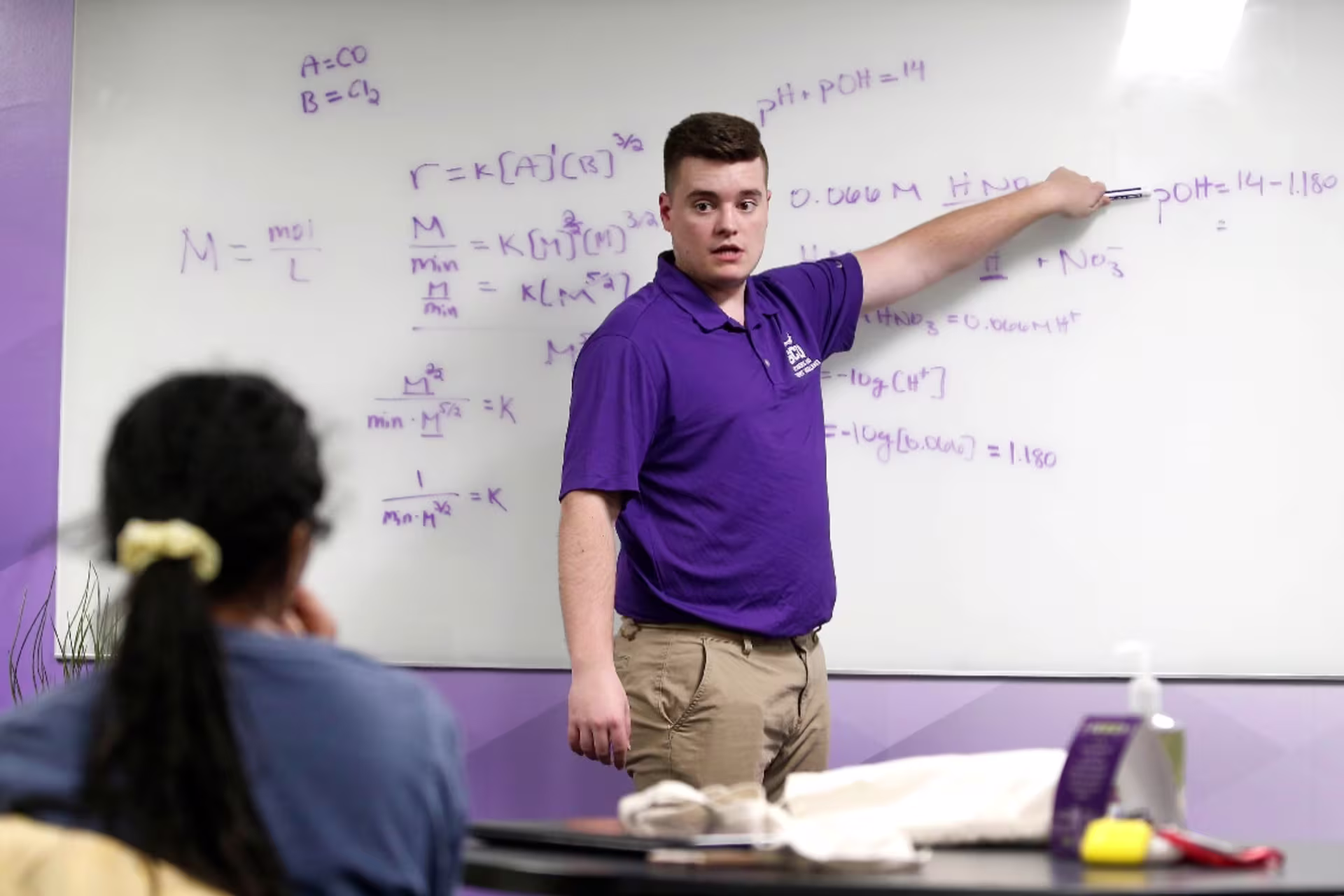 Chemistry professor standing in front of whiteboard with equations on it